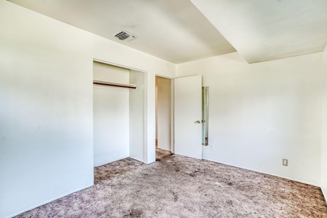 unfurnished bedroom with carpet, visible vents, and a closet