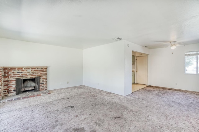 unfurnished living room with visible vents, carpet, a brick fireplace, and ceiling fan