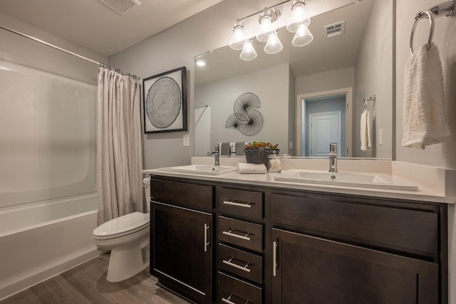 bathroom with toilet, wood finished floors, visible vents, and a sink