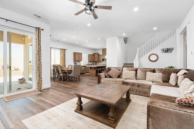 living area with light wood finished floors, visible vents, ceiling fan, stairs, and recessed lighting