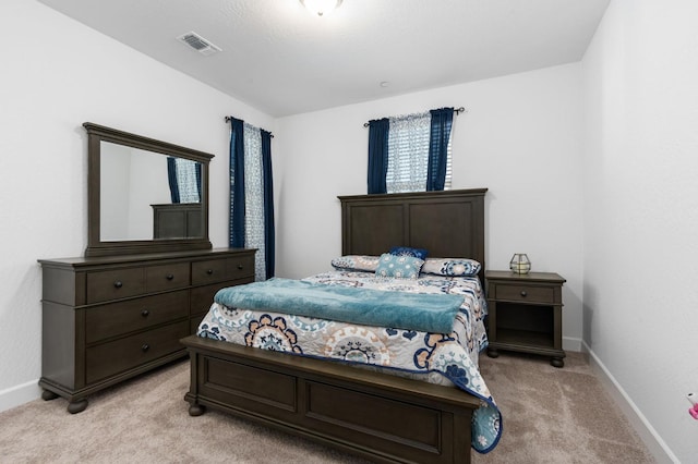 bedroom featuring visible vents, light colored carpet, and baseboards