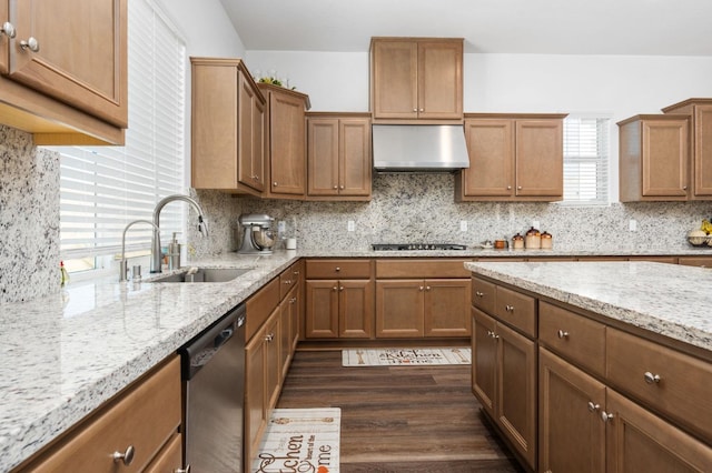 kitchen featuring ventilation hood, light stone countertops, a sink, stainless steel appliances, and backsplash