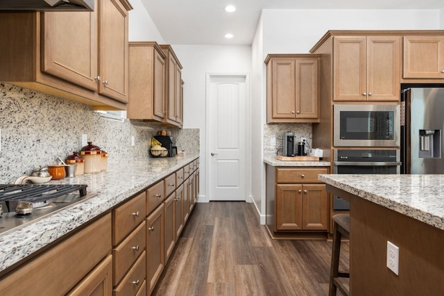 kitchen featuring light stone countertops, dark wood finished floors, recessed lighting, decorative backsplash, and appliances with stainless steel finishes