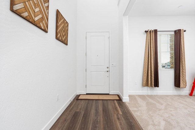 interior space featuring dark colored carpet, baseboards, and dark wood-style flooring