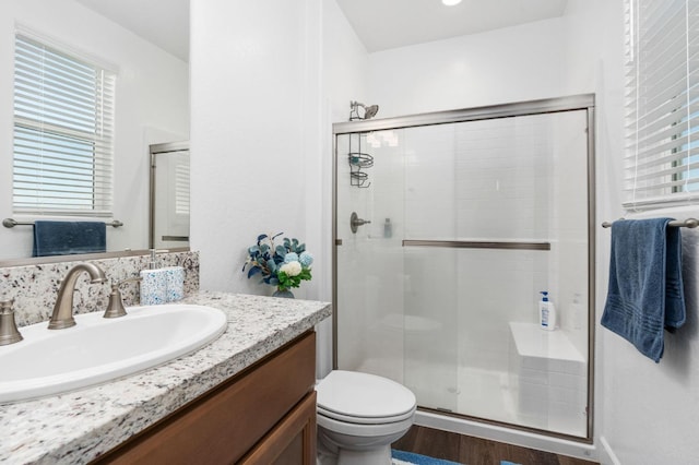 full bath featuring a stall shower, toilet, vanity, and wood finished floors