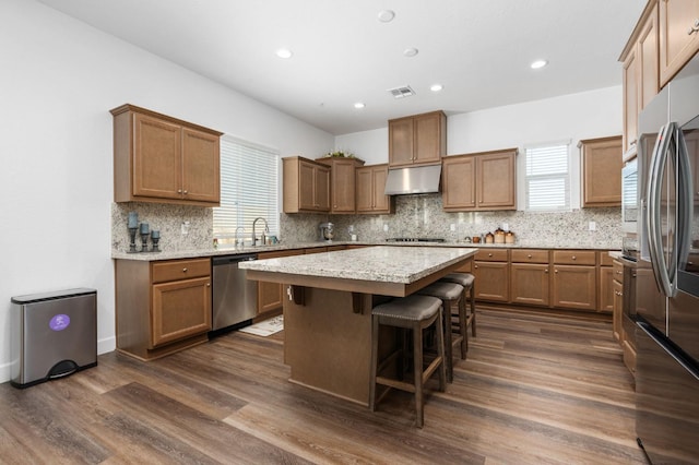 kitchen with visible vents, under cabinet range hood, a center island, appliances with stainless steel finishes, and dark wood-style flooring