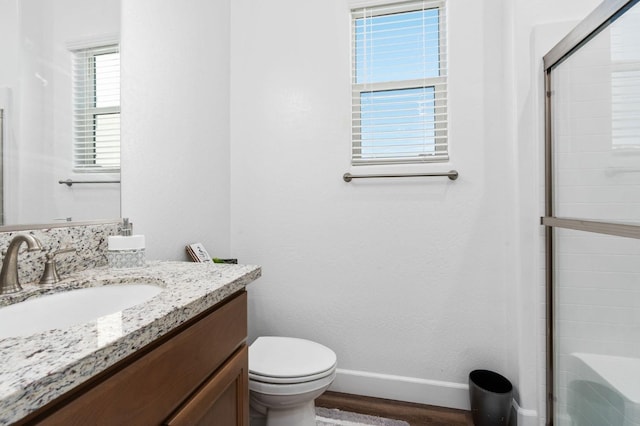 bathroom with baseboards, toilet, a shower with shower door, wood finished floors, and vanity