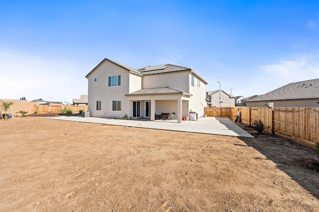 back of property with solar panels, a patio, a fenced backyard, and stucco siding