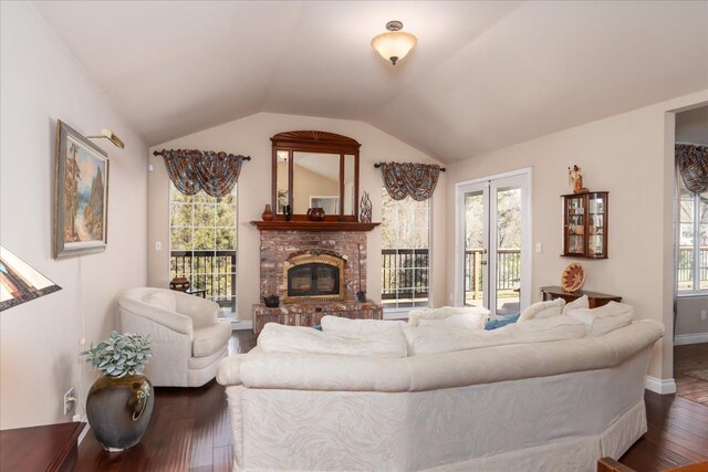 living area featuring plenty of natural light, a fireplace, dark wood-type flooring, and vaulted ceiling