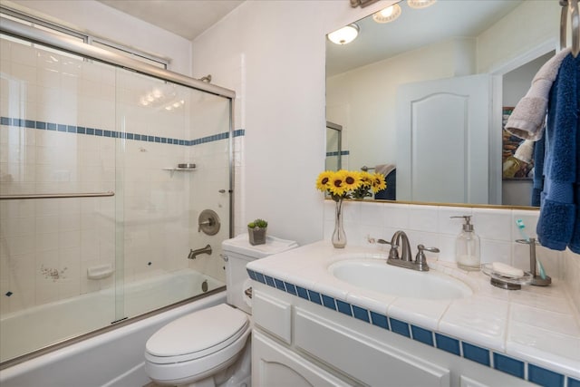 full bathroom featuring shower / bath combination with glass door, tasteful backsplash, toilet, and vanity