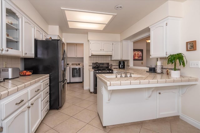 kitchen with a kitchen bar, appliances with stainless steel finishes, a peninsula, white cabinetry, and separate washer and dryer