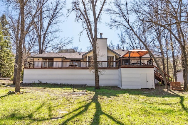 rear view of house with a deck, stairway, a yard, and a chimney