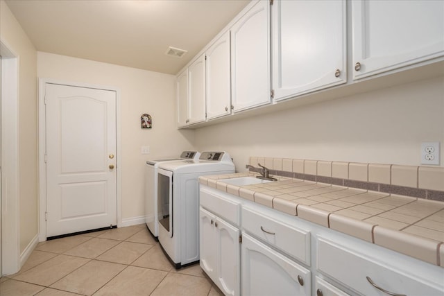 laundry room with visible vents, washer and dryer, a sink, cabinet space, and light tile patterned flooring