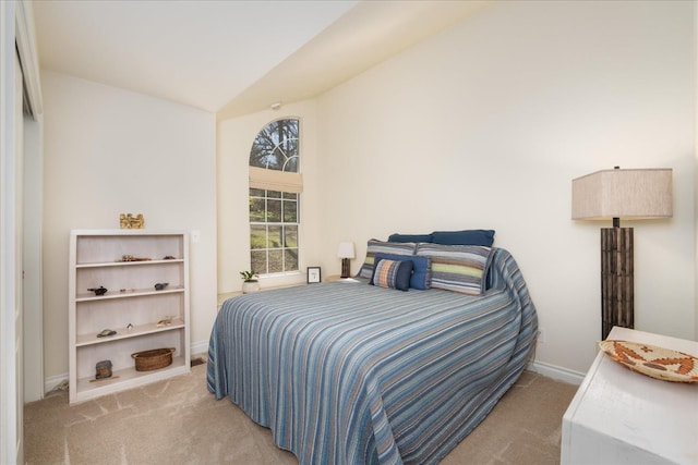 carpeted bedroom with lofted ceiling and baseboards