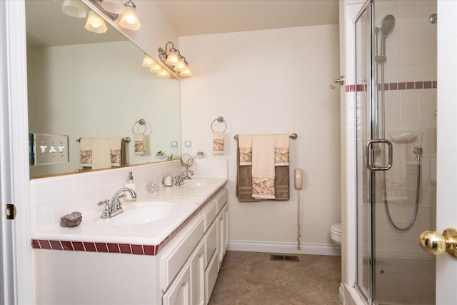 full bath with baseboards, double vanity, a stall shower, a sink, and tile patterned flooring