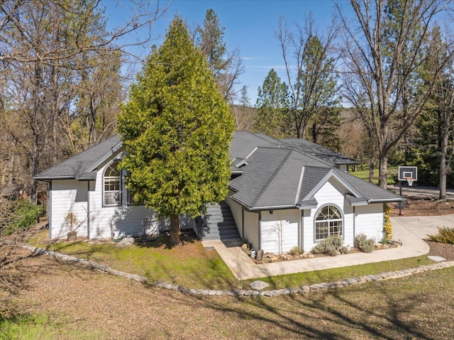 view of front of property featuring a front yard and a shingled roof