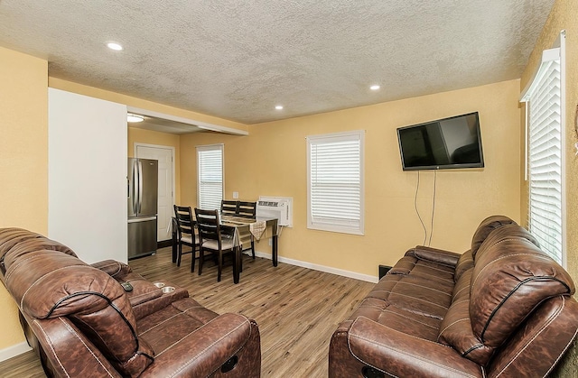 living room with recessed lighting, a textured ceiling, baseboards, and wood finished floors