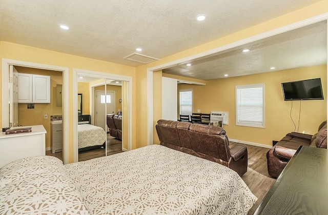 bedroom featuring visible vents, a wall unit AC, recessed lighting, wood finished floors, and a textured ceiling