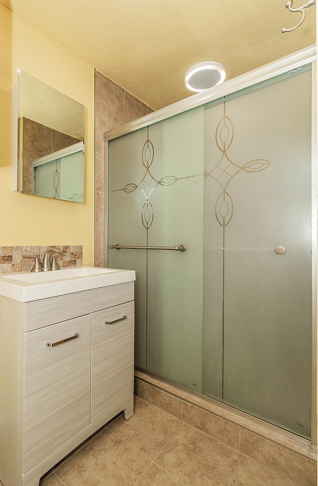 full bath with vanity, a shower with shower door, and tile patterned flooring