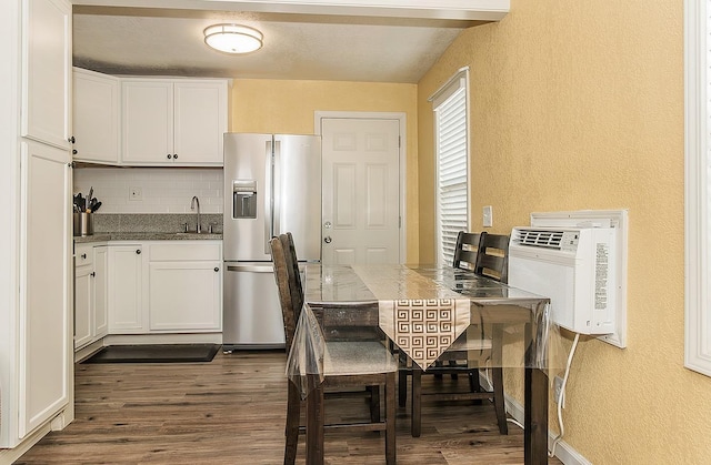 kitchen with backsplash, dark wood finished floors, stainless steel fridge, white cabinetry, and a sink