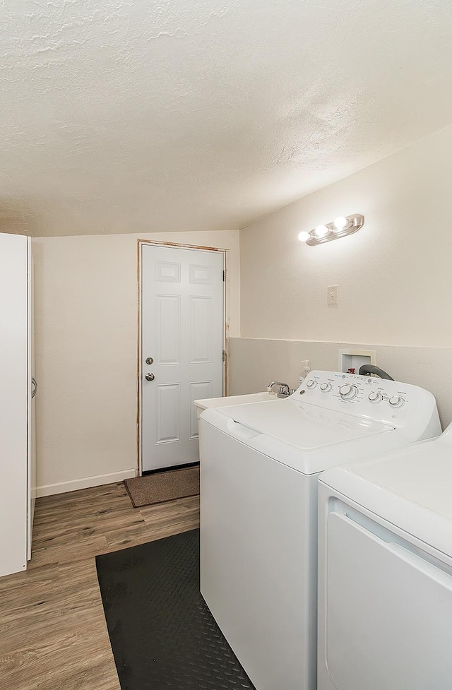 laundry area with baseboards, laundry area, wood finished floors, washer and dryer, and a textured ceiling