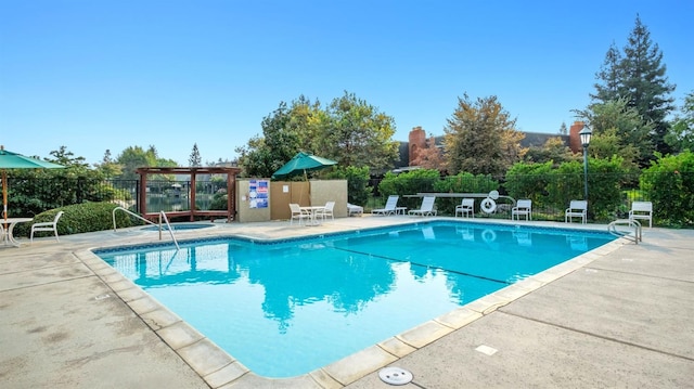 community pool with a patio area and fence