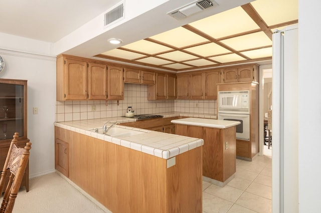 kitchen featuring tasteful backsplash, visible vents, white appliances, and a sink