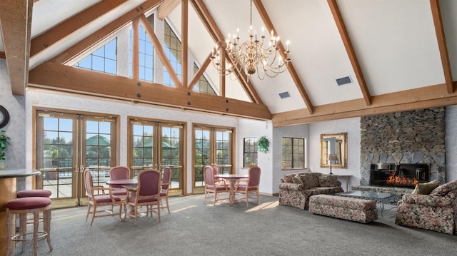 living room featuring a stone fireplace, carpet, french doors, and beamed ceiling