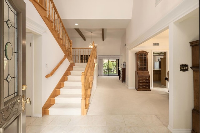 entrance foyer with visible vents, beam ceiling, light colored carpet, and stairs