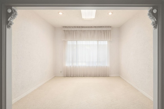 carpeted spare room featuring recessed lighting, a textured wall, and baseboards