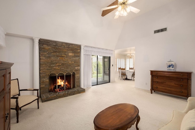 living area featuring visible vents, carpet floors, high vaulted ceiling, a stone fireplace, and ceiling fan with notable chandelier