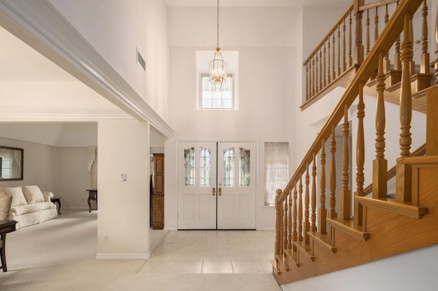 foyer entrance featuring stairway, baseboards, tile patterned flooring, a towering ceiling, and a chandelier