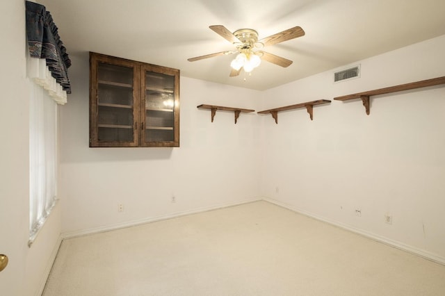 carpeted empty room with visible vents, baseboards, and a ceiling fan