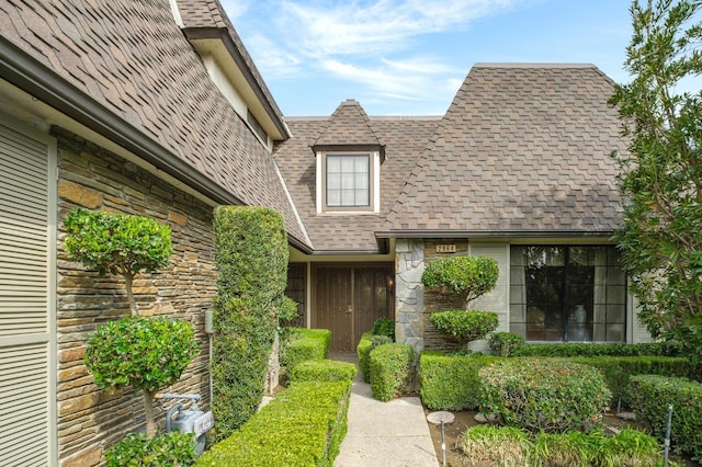 property entrance with stone siding and a shingled roof