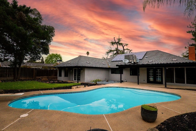 pool at dusk with a patio area, a fenced in pool, french doors, and fence