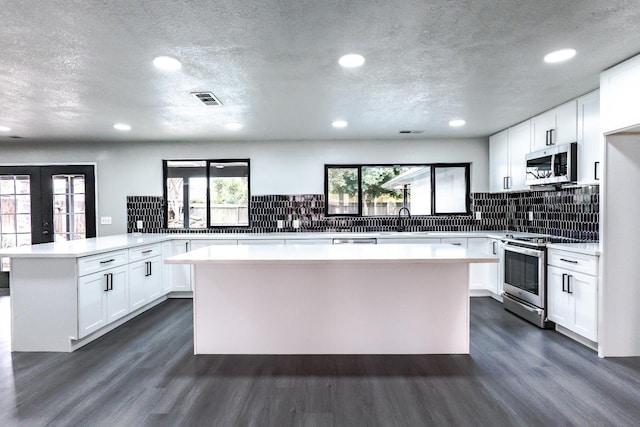 kitchen with visible vents, appliances with stainless steel finishes, a peninsula, and dark wood-style flooring