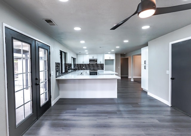 kitchen with dark wood-type flooring, tasteful backsplash, white cabinetry, french doors, and a peninsula