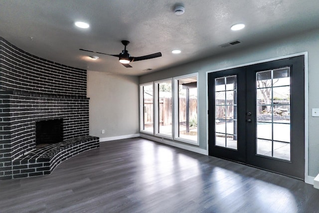 unfurnished living room featuring wood finished floors, baseboards, visible vents, french doors, and a textured ceiling