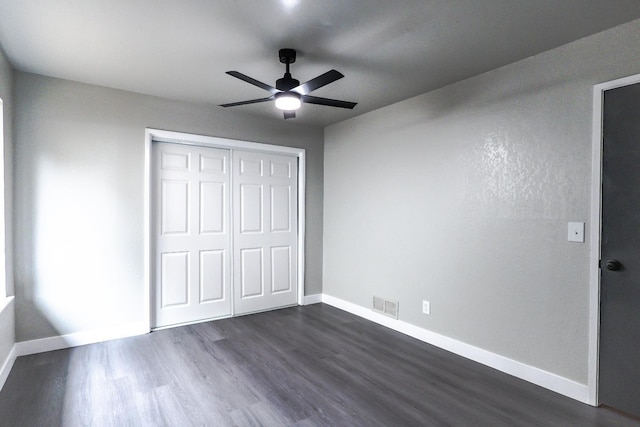 unfurnished bedroom featuring a closet, visible vents, dark wood-type flooring, and baseboards