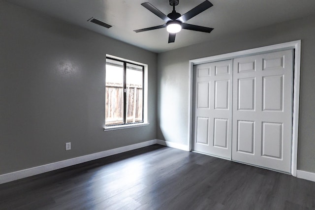 unfurnished bedroom featuring visible vents, dark wood-type flooring, ceiling fan, baseboards, and a closet