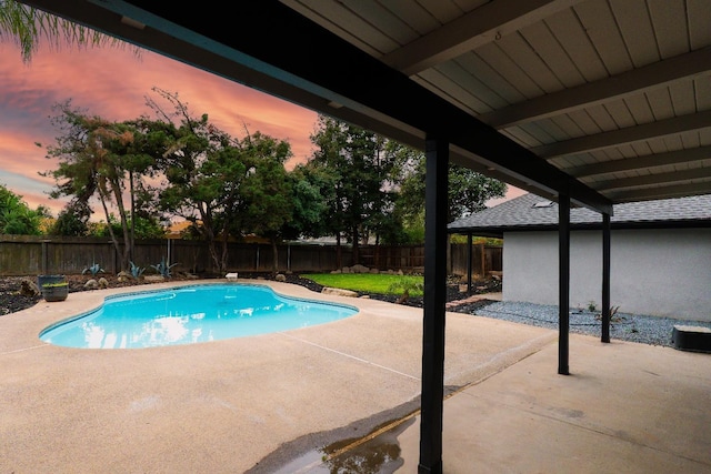 pool at dusk with a fenced in pool, a fenced backyard, and a patio area