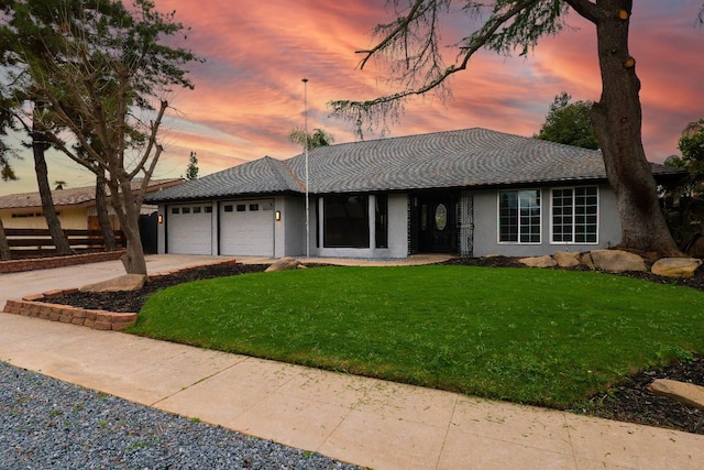 single story home featuring fence, driveway, an attached garage, stucco siding, and a front lawn