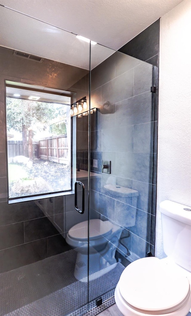 full bath featuring visible vents, toilet, and a stall shower