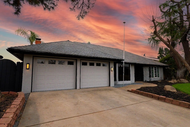 ranch-style home featuring stucco siding, a garage, concrete driveway, and a chimney