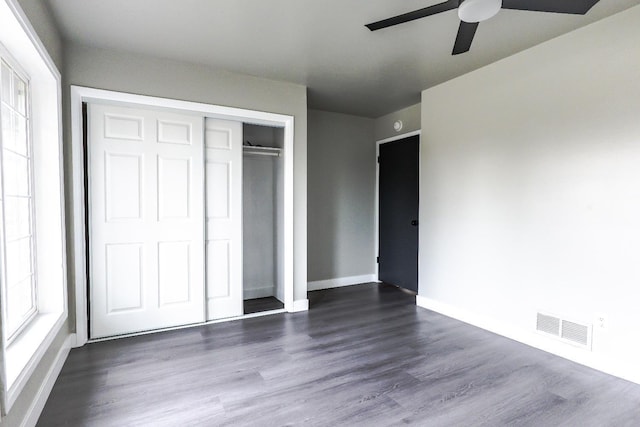 unfurnished bedroom with dark wood-style floors, visible vents, baseboards, and a closet