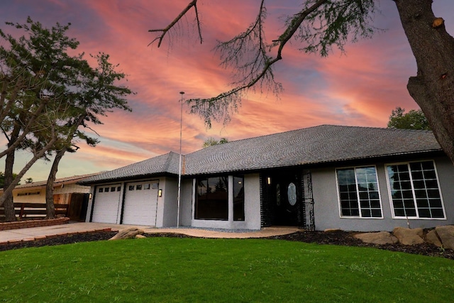 single story home with stucco siding, an attached garage, driveway, and a front yard