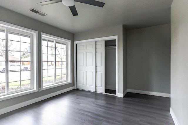 unfurnished bedroom with visible vents, dark wood-type flooring, baseboards, a closet, and a ceiling fan