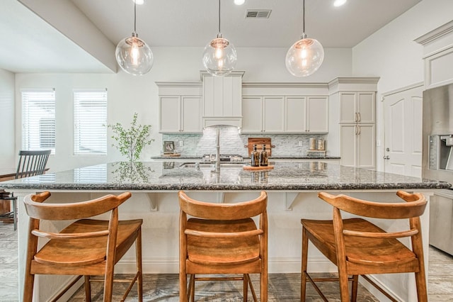 kitchen featuring tasteful backsplash, visible vents, a breakfast bar, and hanging light fixtures