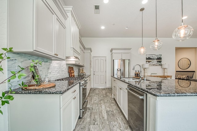 kitchen with a center island with sink, visible vents, a sink, appliances with stainless steel finishes, and backsplash