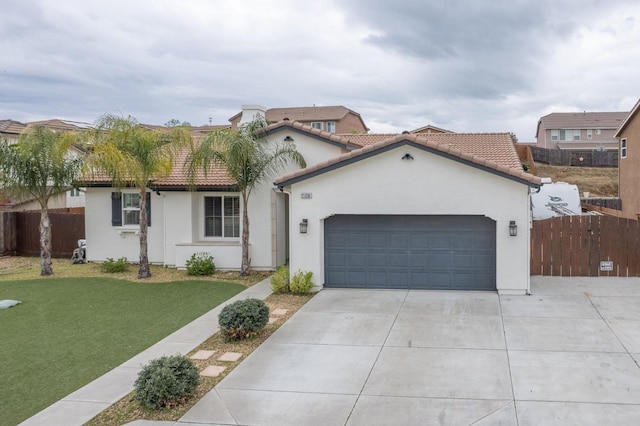 mediterranean / spanish home with a front yard, fence, an attached garage, stucco siding, and concrete driveway